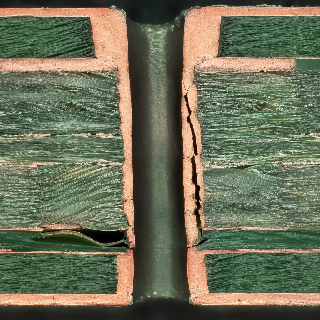 PCB cross-section under optical microscope showing via barrel crack and copper layer delamination with bright field illumination, metallographic microsection sample in epoxy mount